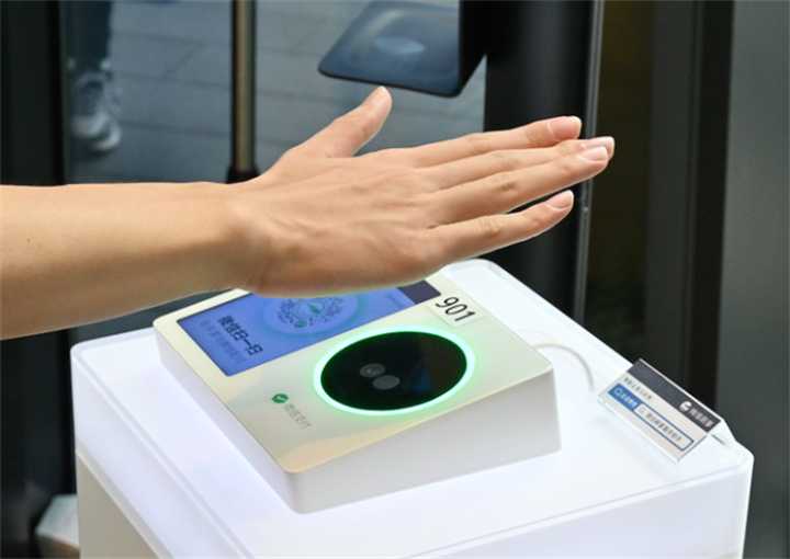 Person placing palm over WeChat palm print payment scanner, demonstrating contactless biometric checkout hardware