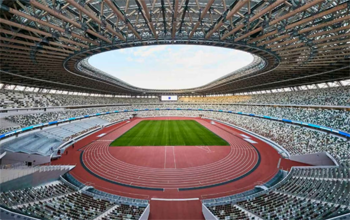 Empty large modern Olympic athletics stadium with running track and grass field, illustrating venue idle capacity after Games