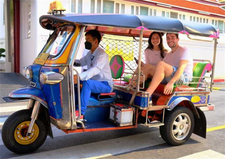 Colorful Thai gasoline tuk-tuk carrying tourist passengers, a classic Southeast Asian urban transport vehicle