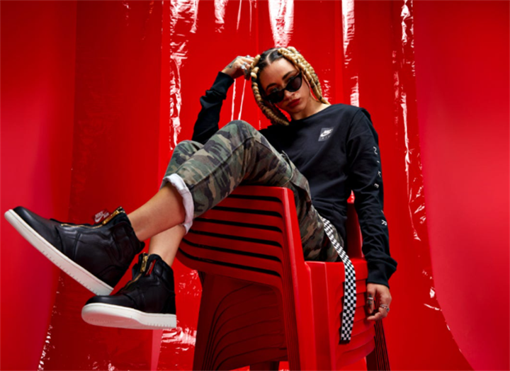 Young woman in streetwear camo cargo pants and black high-top sneakers, representing casual sneaker-centric fashion culture