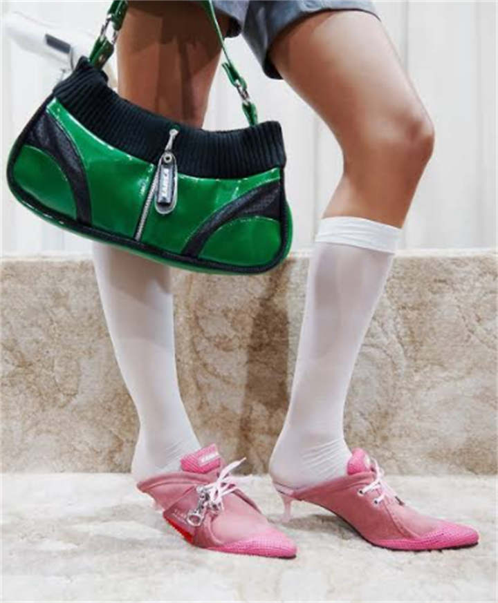 Close-up shot of vintage pink pointed heel mules paired with white knee-high socks and glossy green shoulder bag, showcasing traditional heel-focused styling