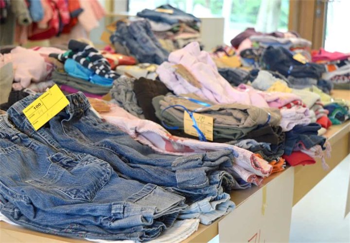 Neatly sorted tagged secondhand denim and clothing laid out for resale in a thrift retail shop, final stage of used clothing supply chain