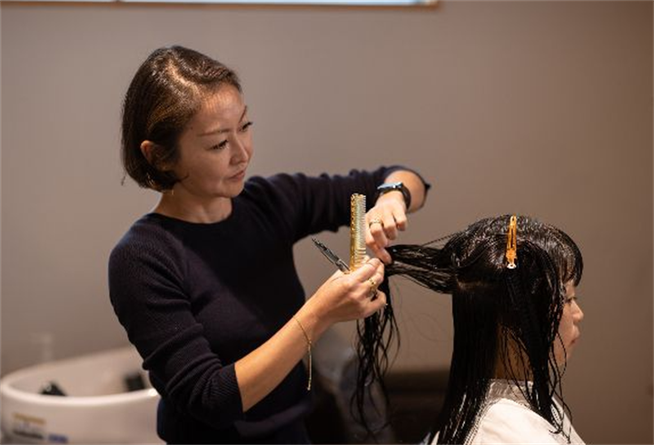 Female hairdresser cutting long wet client hair in a modern salon space