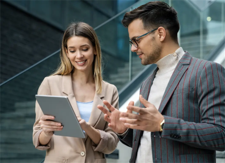 Two business professionals reviewing legal debt protection documents on a digital tablet outside an office
