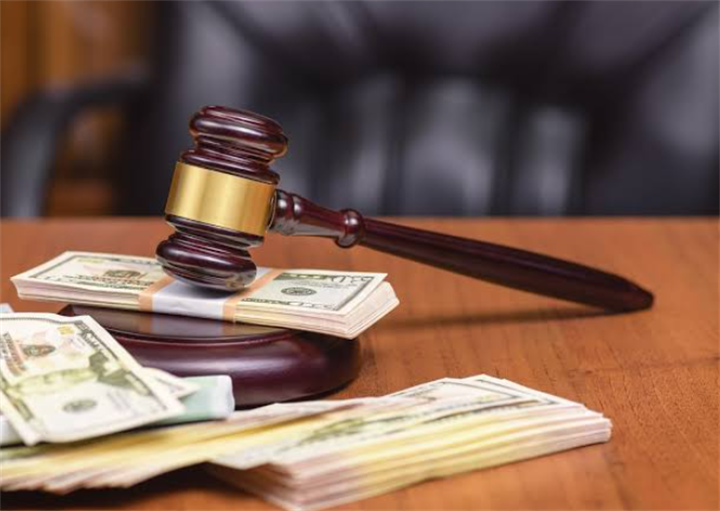 Wooden judge gavel resting on stacks of US cash, symbolizing financial debt regulation and legal debtor safeguards