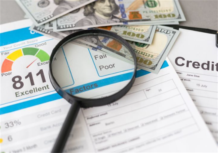 Magnifying glass resting on credit score report with US dollar bills, showing credit record checking