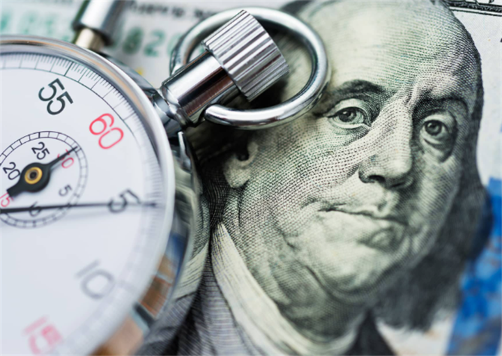 Stopwatch resting on US hundred-dollar bill, representing time-sensitive fake transfer fraud tactics targeting debtors