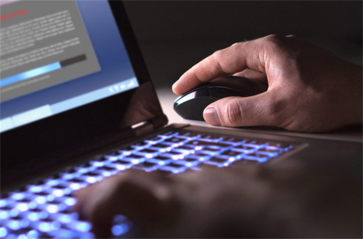Person using a laptop mouse while browsing suspicious financial web content on screen