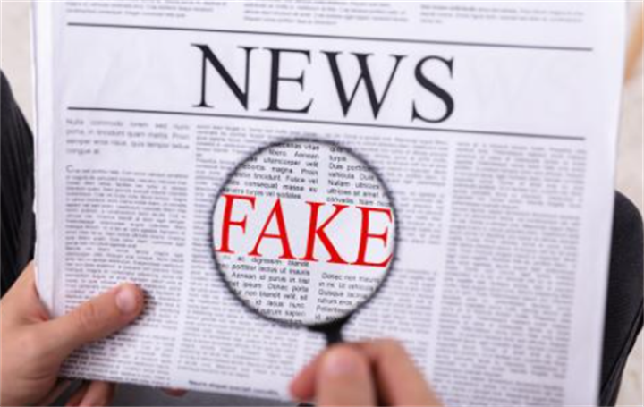 Magnifying glass highlighting the word FAKE on a newspaper page, symbolizing fact-checking deepfake financial news