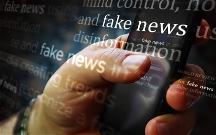 Hand holding smartphone layered over floating text of fake news and disinformation, representing social media misinformation