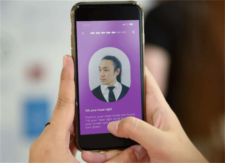 Person using a smartphone to complete liveness detection by tilting their head during identity verification