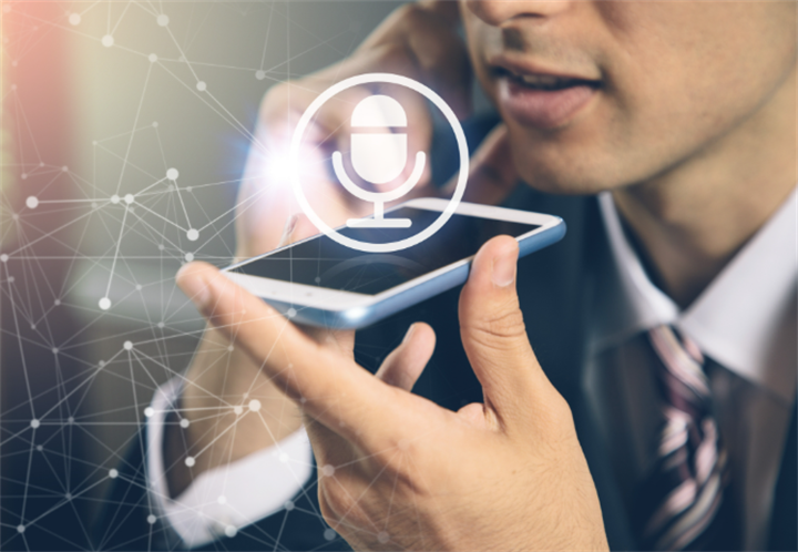 Businessman speaking into smartphone with microphone icon overlay, demonstrating voice recognition for remote banking login